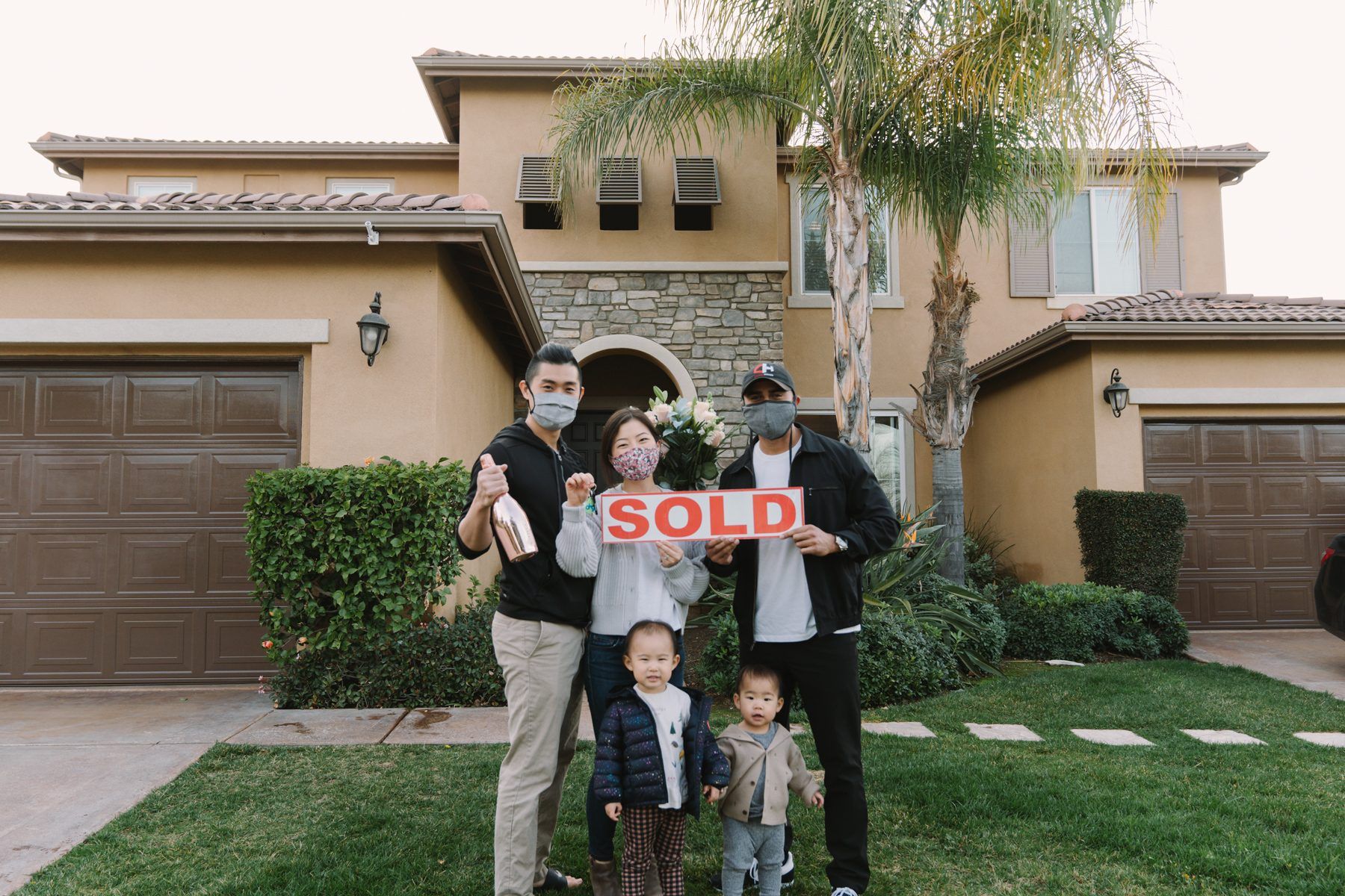 Clients of The Chavez Team at The Agency holding their new keys and the SOLD sign on closing day in Orange County